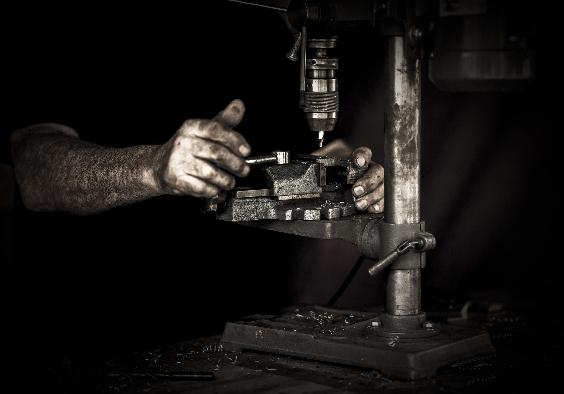 Hands steadying a part at a drill press