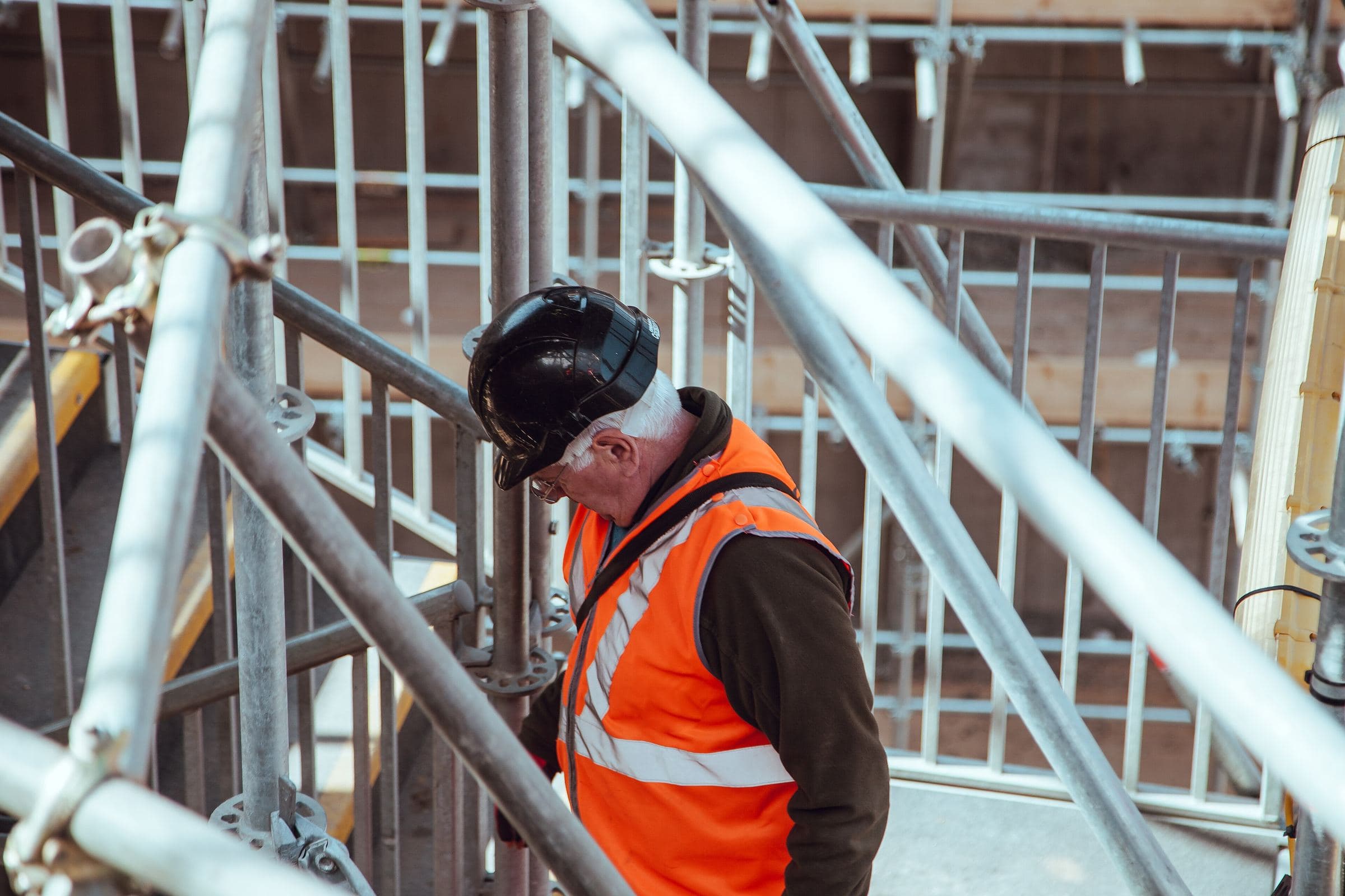 A worker in a hard hat and hi-vis vest on scaffolding